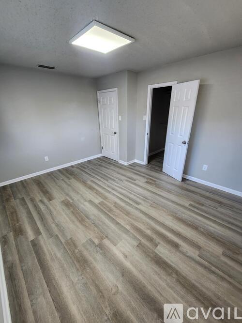 A room with wooden flooring and two white doors.