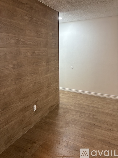 A room with wooden flooring and a wall with wood paneling.