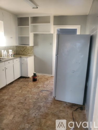 A kitchen with white cabinets and a grey fridge.
