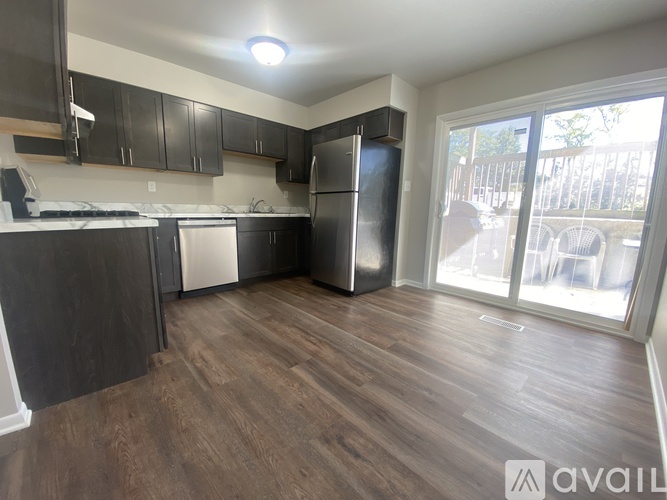 A kitchen with dark wood floors and a stainless steel refrigerator.