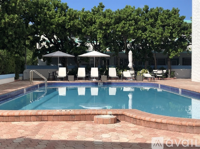 A pool surrounded by trees and chairs.