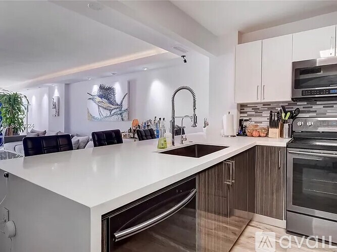 A modern kitchen with a white countertop and stainless steel appliances.