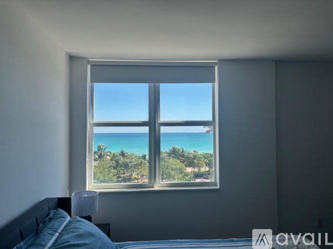 A bedroom with a large window overlooking a beach.