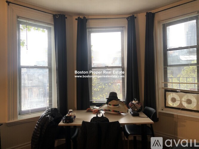 A dining room with a table set for two and a window with blinds.