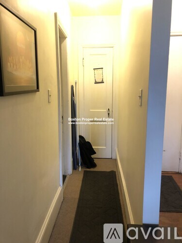 A hallway with a black carpet and a painting on the wall.