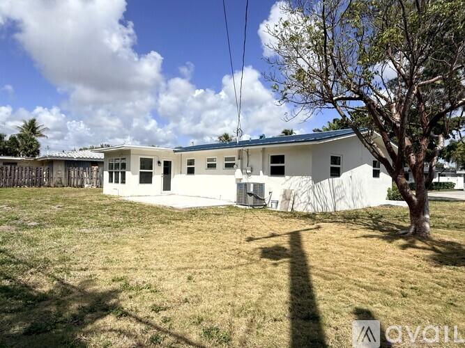 A white building with a blue roof is surrounded by a grassy field.