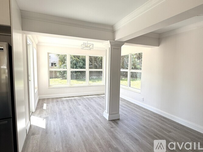A spacious room with a large window and a view of trees outside.