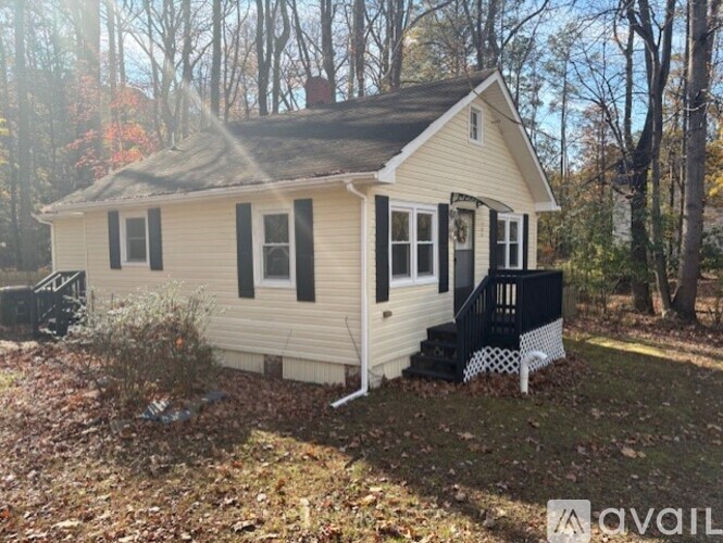 A small house with a black door and a black railing on the porch.