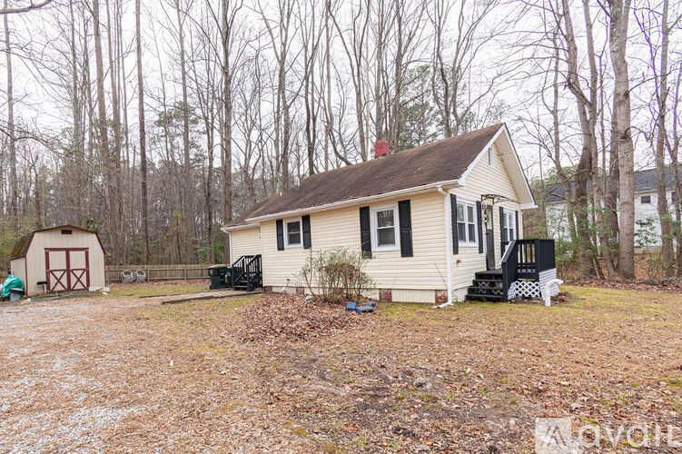 A small house with a red door is surrounded by trees.