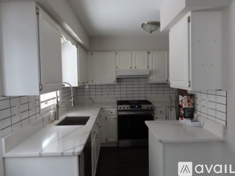 A kitchen with white cabinets and a black stove top.