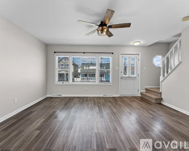 A room with a ceiling fan and wooden flooring.