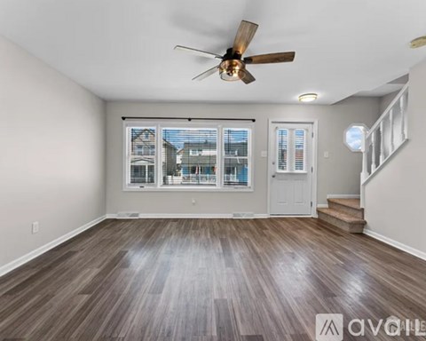 A room with a ceiling fan and wooden flooring.