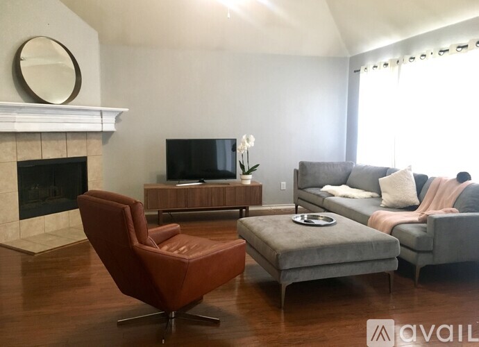 A living room with a fireplace, a chair, a sofa, and a television.