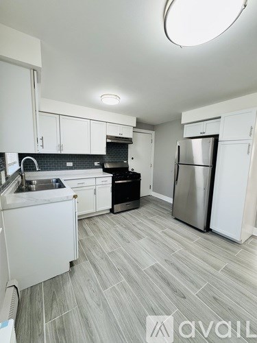 A kitchen with white cabinets and a grey floor.