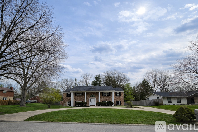 A house with a front yard and a tree in the background.