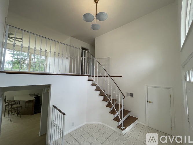 A living room with a dining table and chairs is visible from the staircase.