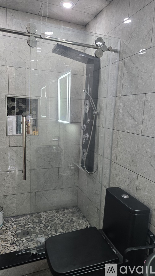 A bathroom with a glass shower door and a black toilet.