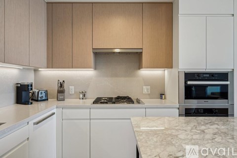 A kitchen with white cabinets and a marble countertop.