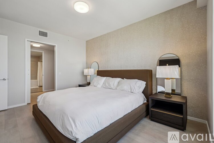A bedroom with a large bed and a nightstand with a lamp.