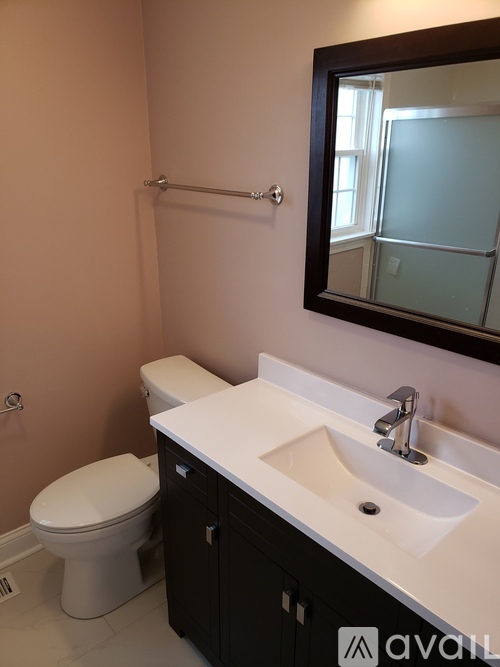 A bathroom with a toilet, sink and mirror.