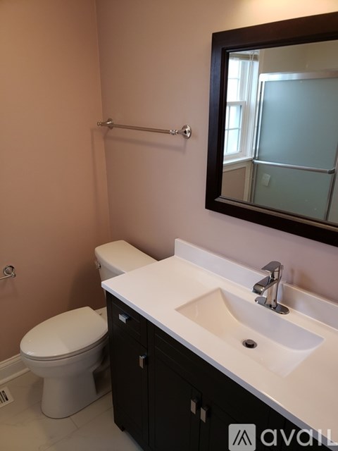 A bathroom with a toilet, sink and mirror.