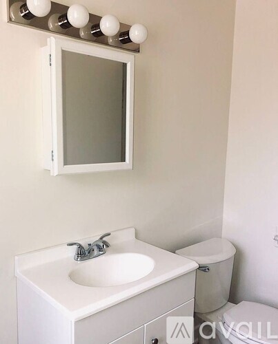 A white bathroom with a sink, mirror, and toilet.