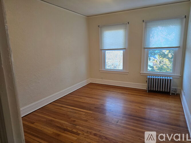 A room with wooden floors and a window with a view of trees outside.