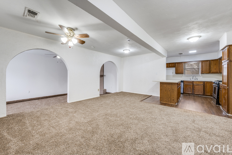 A spacious room with a ceiling fan and beige carpeting.
