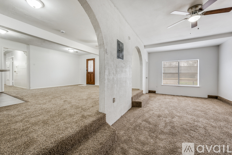 A spacious room with a carpeted floor and a ceiling fan.