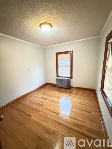 A room with wooden floors and a window with blinds.