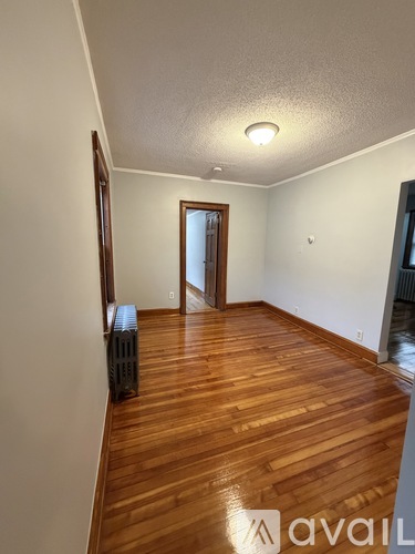A room with wooden flooring and a doorway leading to another room.