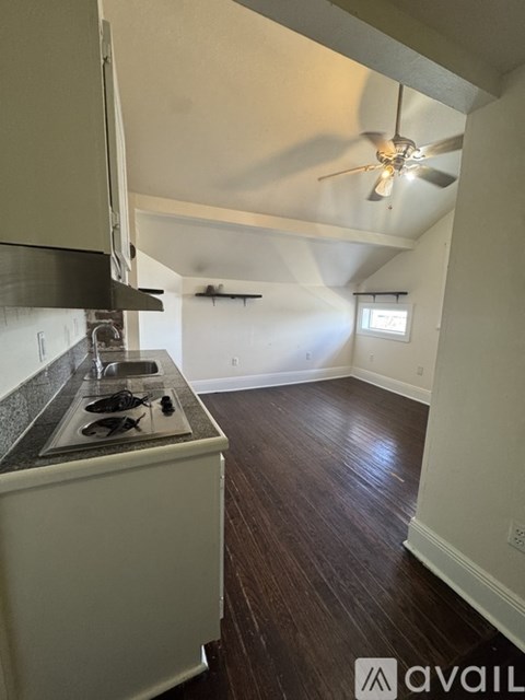 A kitchen with a white counter top and a fan on the ceiling.