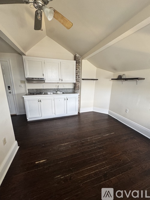 A room with a fan and wooden floors.