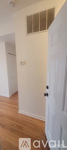 A white door with a black handle is in a room with wooden floors and white walls.