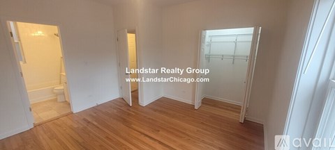 A room with wooden floors and white walls, with a doorway leading to another room.