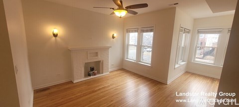 A living room with a fireplace and a ceiling fan.