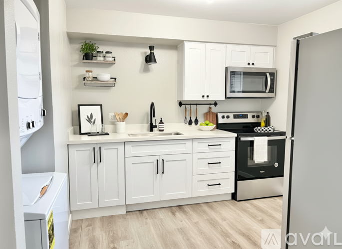 A kitchen with white cabinets and a grey fridge.