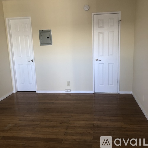 A room with two white doors and a wooden floor.