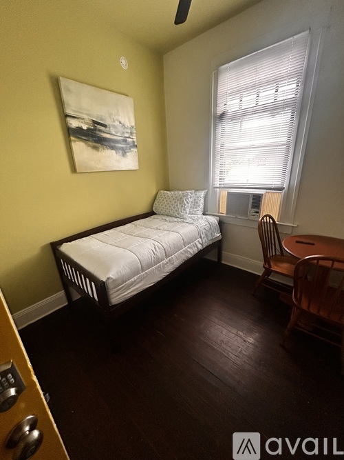 A bedroom with a bed, chair, and painting on the wall.