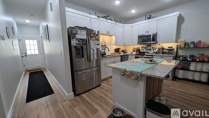 A kitchen with white cabinets and a wooden floor.