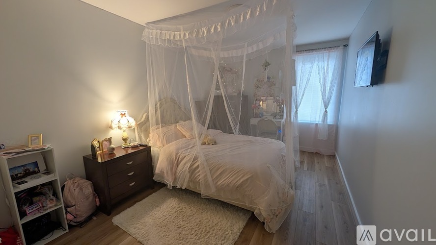 A bedroom with a canopy bed and a TV mounted on the wall.
