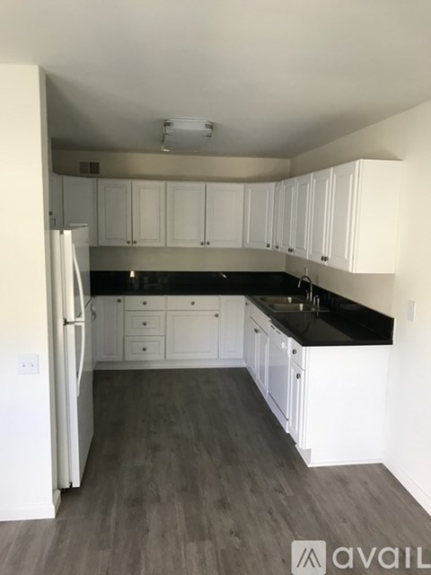 A kitchen with white cabinets and a black countertop.