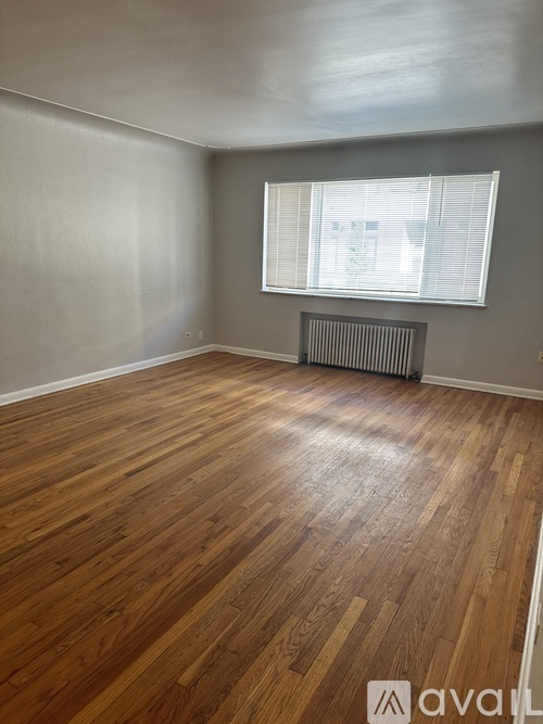 A room with wooden flooring and a window with blinds.