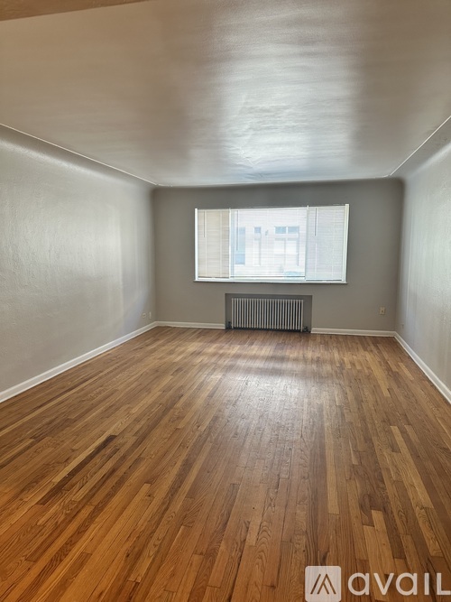 A room with wooden flooring and a window with blinds.