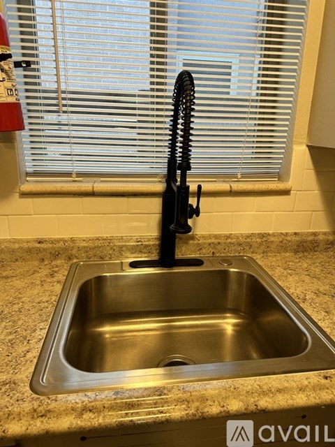 A stainless steel kitchen sink with a black faucet.