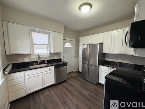 A kitchen with white cabinets and a black countertop.