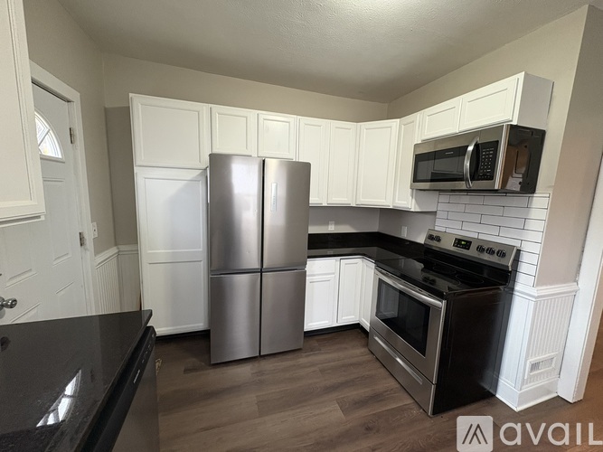 A kitchen with white cabinets and a black countertop.