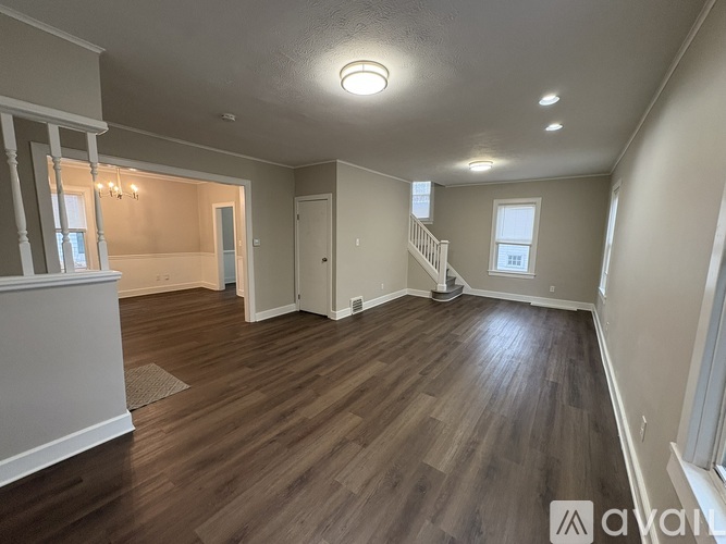 A spacious room with wooden flooring and a staircase.