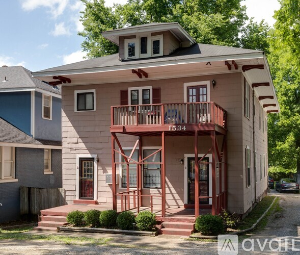 A two-story house with a balcony and a red door.