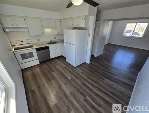 A kitchen with white appliances and wooden floors.